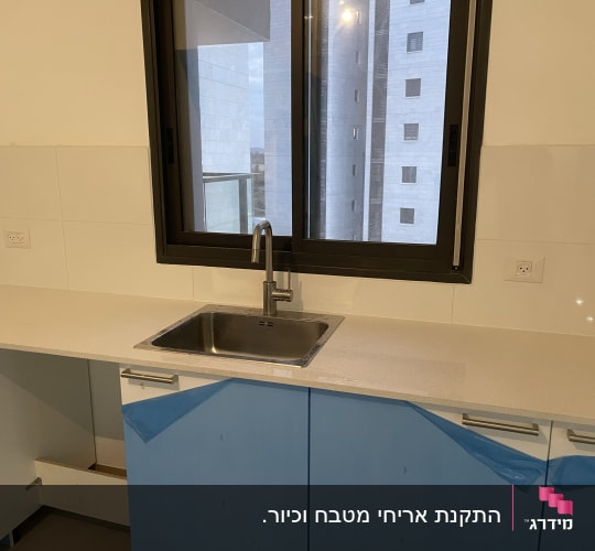 מטבח בשיפוץ עם ארונות מכוסים בניילון כחול
